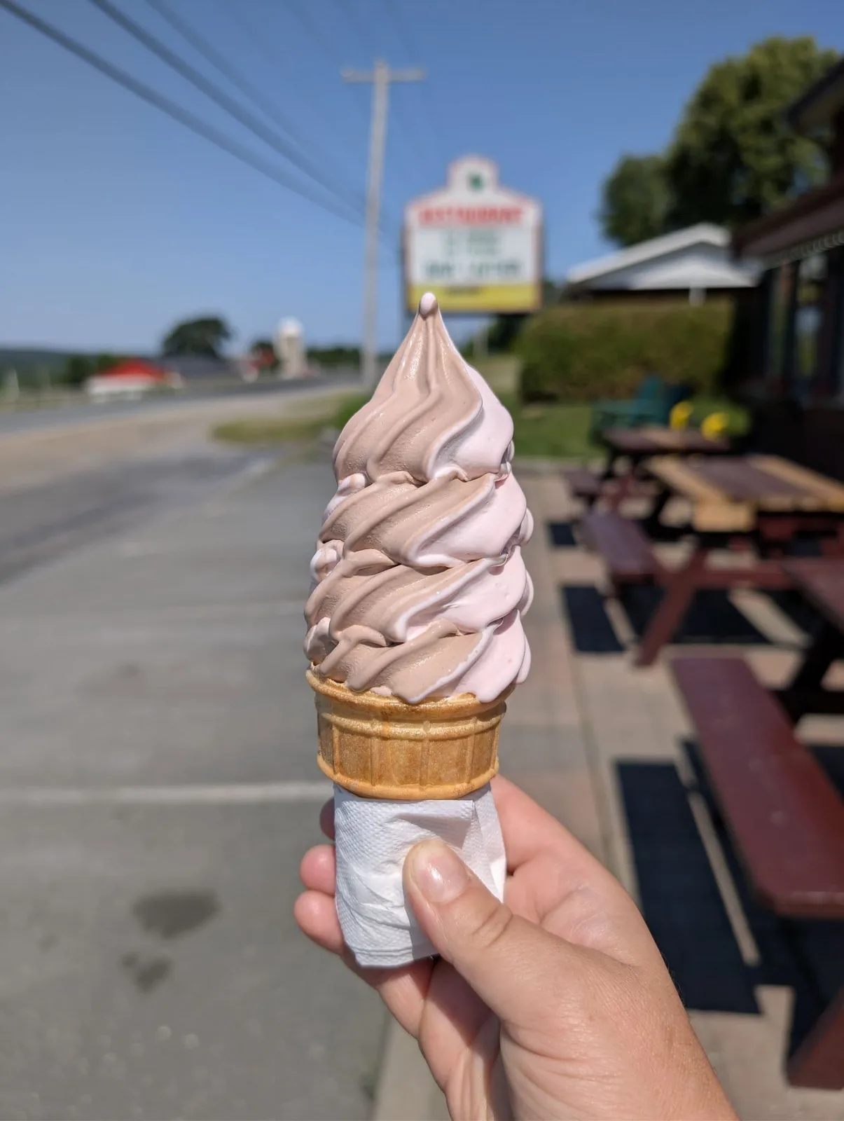 Cornet de crème glacée molle tourbillon chocolat et fraise devant le stationnement du restaurant
