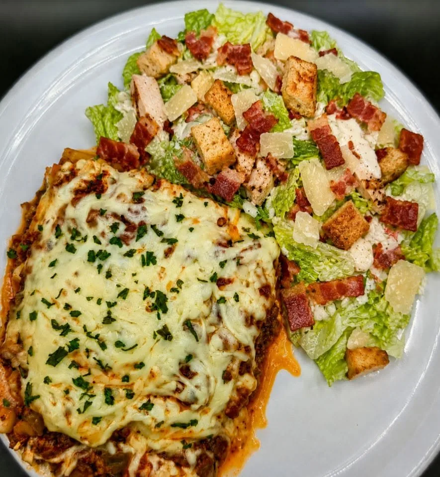 Lasagne gratinée servie avec une salade César au bacon et parmesan