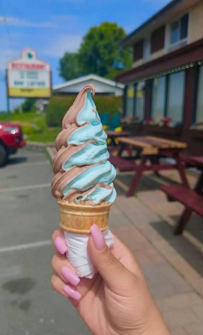 Cornet de crème glacée molle tourbillon chocolat et bleu, avec l'enseigne du restaurant en arrière-plan